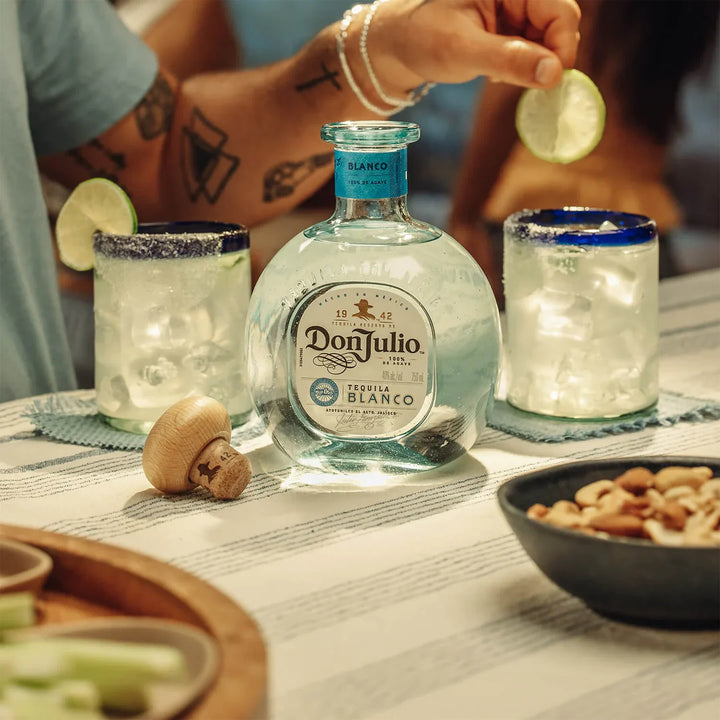 Don Julio Blanco tequila bottle and margaritas on a table