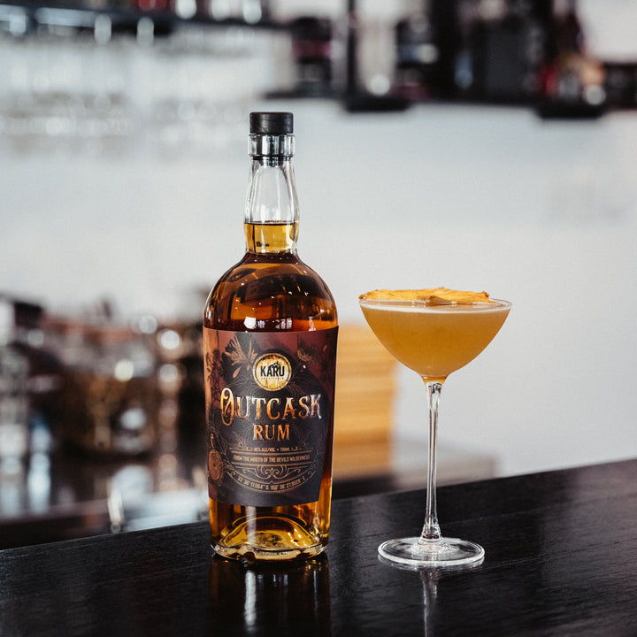 Karu Distillery Outcask Rum bottle beside a cocktail
